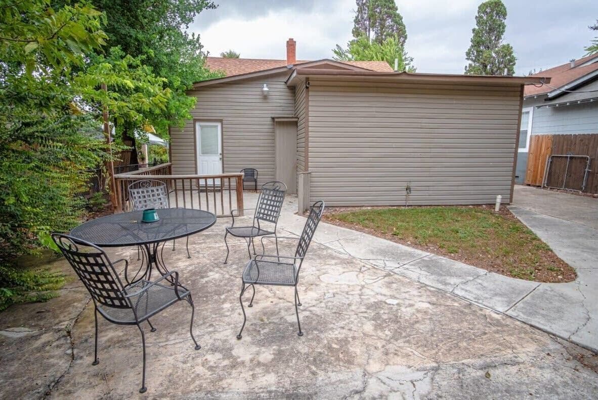 A patio with a table and chairs, a small shed, and a fenced yard.