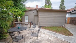 Eine Terrasse mit Tisch und Stühlen, eine kleine Gartenhütte und ein umzäunter Garten.