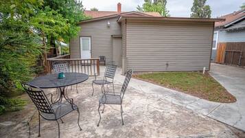 A patio with a table and chairs, a small shed, and a fenced yard.