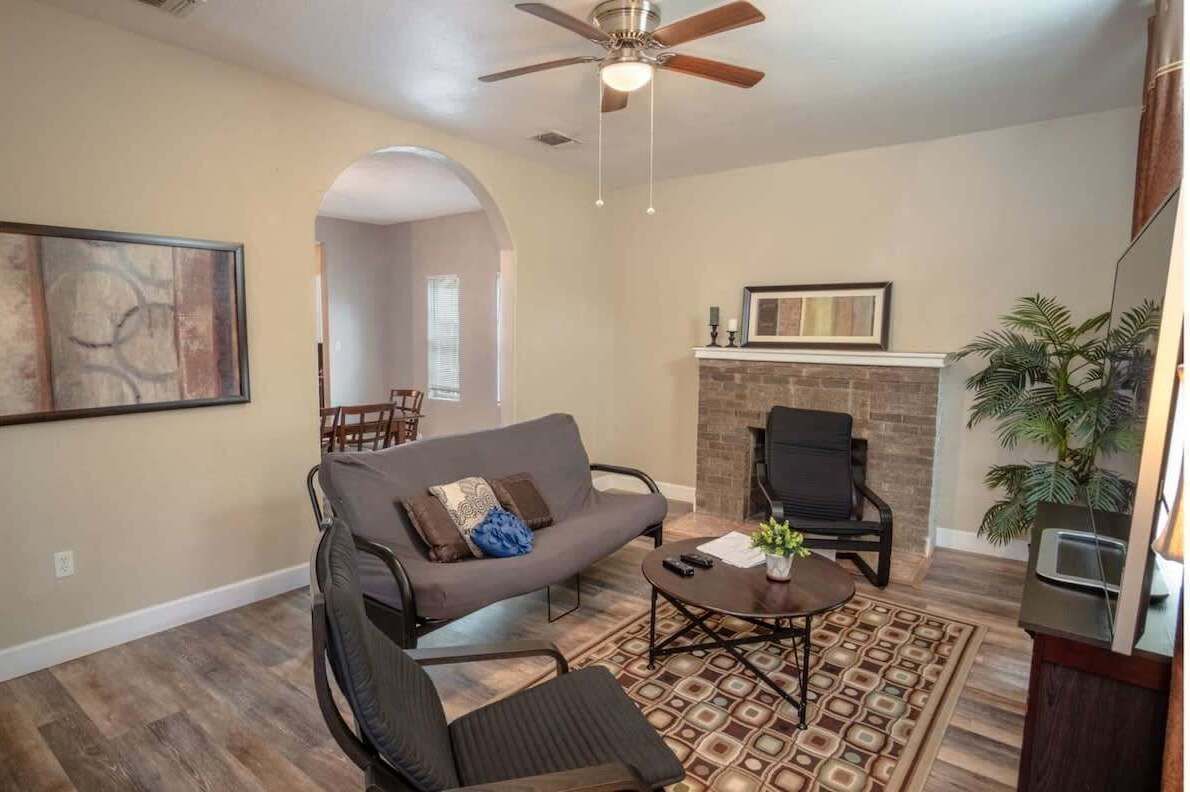 A living room with a sofa, armchairs, a coffee table, a fireplace, and a ceiling fan.