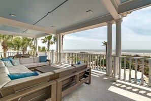 A covered outdoor seating area with a view of the beach.