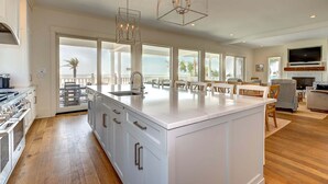 A spacious kitchen with a large island, white cabinetry, and a view of the ocean. - 🌅Coastal Sunrise🌅Ocean Front on Ocean Blvd. Private Pool/hot tub, stunning ocean views! (Isle Of Palms)