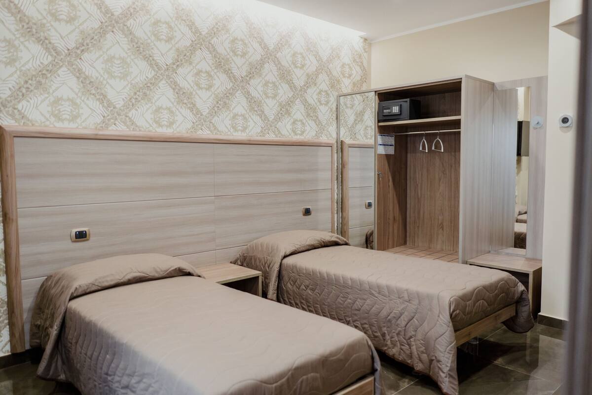 A bedroom with two single beds, a wardrobe, and a small table.