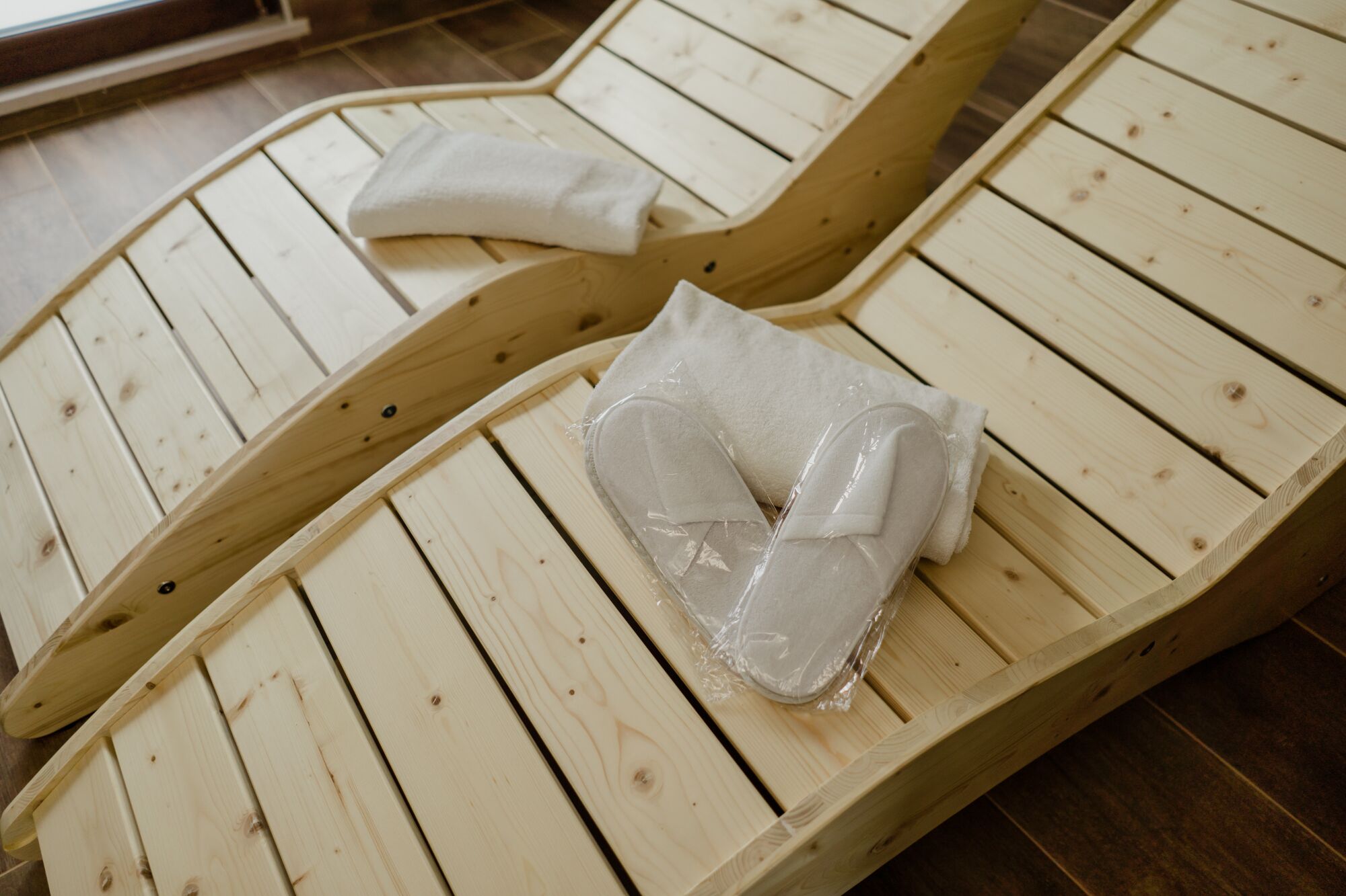 Due poltrone in legno con asciugamani bianchi e rivestimenti in plastica.