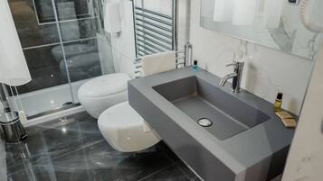 Une salle de bain moderne avec un lavabo gris, des toilettes blanches et une douche à parois de verre.