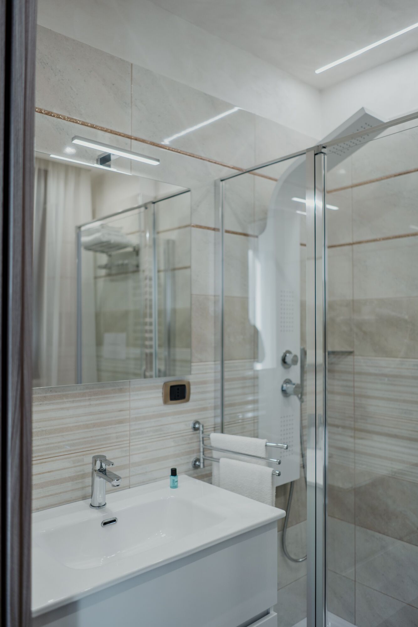 Une salle de bain moderne avec une douche à parois de verre, un lavabo blanc et un grand miroir.