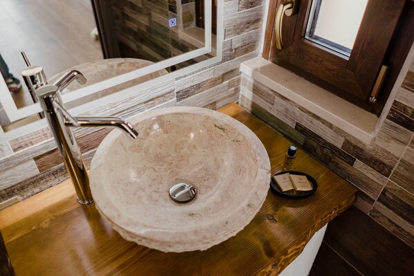 A bathroom with a marble sink, a modern faucet, and a wooden vanity.