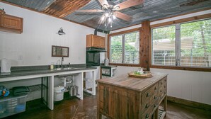 Cocina con isla de madera, lavamanos, armarios y ventana con vista a follaje.