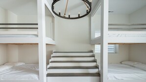 Un dormitorio con literas, una escalera y una araña.