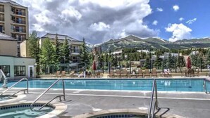 Un área de piscina con varios jacuzzis y vistas a montañas al fondo.