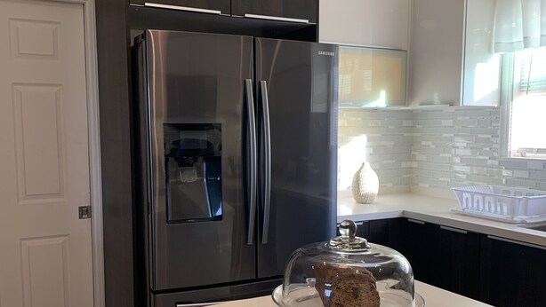 A modern kitchen with a stainless steel refrigerator, a white countertop, and a glass cake stand with a cake. - Beautiful Full House Rental in Private Gated Community,  Montego Bay, Jamaica (Montego Bay)