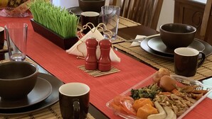 A dining table set with various dishes, including a pineapple, a bowl of greens, and a tray of vegetables. - Beautiful Full House Rental in Private Gated Community,  Montego Bay, Jamaica (Montego Bay)