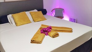 Ein ordentlich bezogenes Bett mit gelb-weißen Kissen, einer gerahmten Weltkarte und einer Ananas als Wanddekoration.