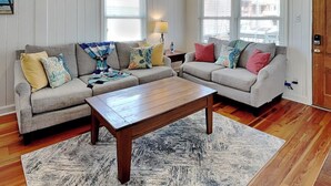 A living room with two grey sofas, a wooden coffee table, and a patterned rug. - Good Vibrations | Pet-friendly w/ Beach Views (Carolina Beach)