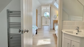 A bedroom with a skylight, a bathroom with a sink and mirror, and a hallway with a radiator. - Idyllic coastal cottage with private beach hut - Sea Rose Cottage (Kingsdown)