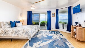 Un dormitorio con cama, mesita de noche, televisor y vista al océano.