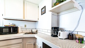 A kitchen with white cabinets, a microwave, a coffee maker, and a toaster.