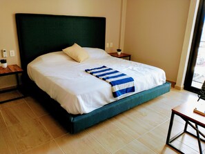 A neatly made bed with a blue and white striped blanket, a green headboard, and a bedside table with a small plant. - Kaab AtP new Apt with rooftop pool, cozy. (Playa del Carmen)