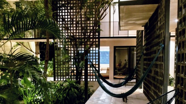 Ein modernes Interieur mit einer Hängematte, einem Holztisch und üppigem Grün.