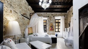A rustic room with stone walls, a wooden ceiling, a bed with a canopy, a bedside table, a small desk, and a chair. - Antonia's rustic house - Old town view (Ρέθυμνο)