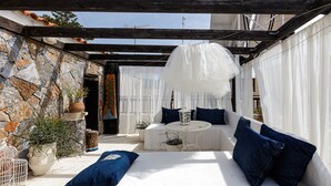 A cozy outdoor seating area with a stone wall, a white bench, and blue cushions. - Antonia's rustic house - Old town view (Ρέθυμνο)