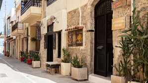 A row of buildings with balconies, a sign reading "Antonia's House," and potted plants on the sidewalk. - Antonia's rustic house - Old town view (Ρέθυμνο)
