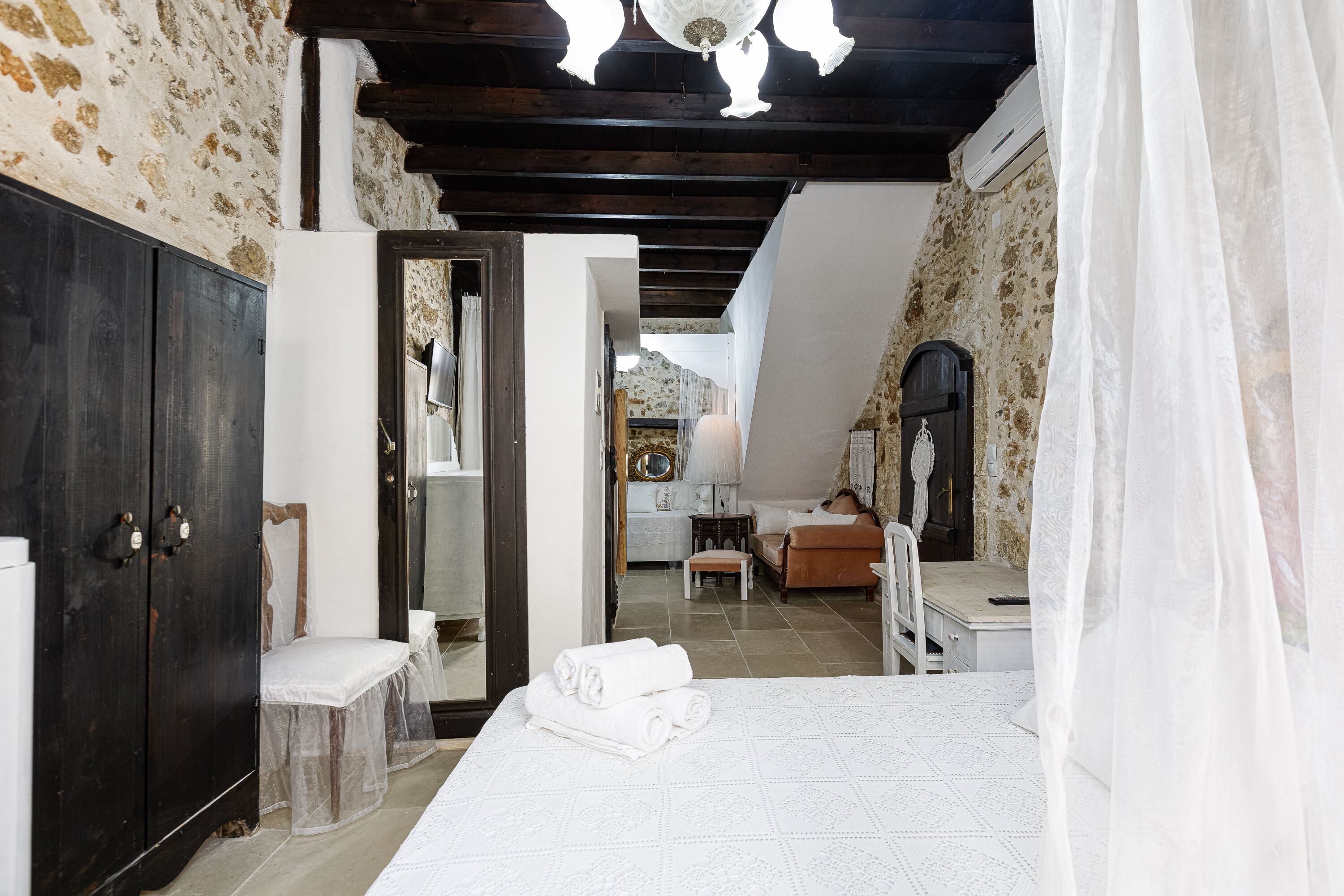 Un dormitorio con cama, armario, espejo y puerta que da a otra habitación.