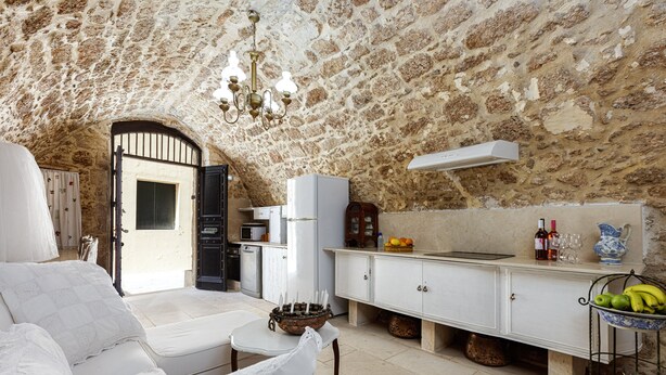 A cozy, stone-walled room with a bed, a dining area, and a kitchen. - Antonia's rustic house - Old town view (Ρέθυμνο)
