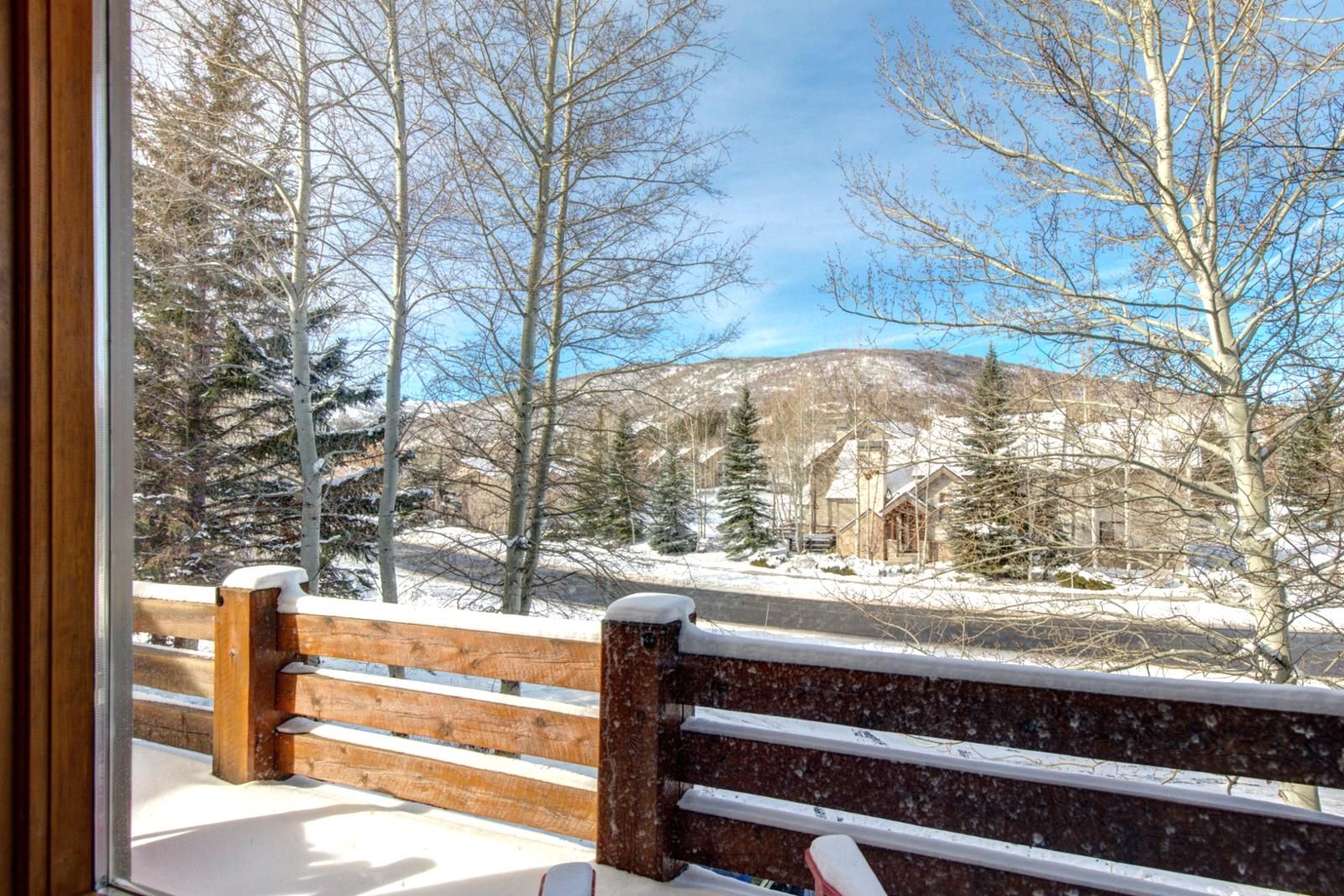 A wooden bench with a snowy landscape and a mountain in the background.