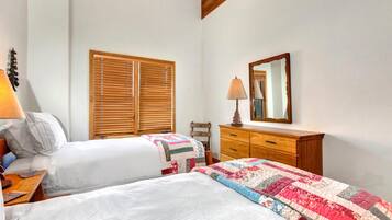A bedroom with two beds, wooden blinds, a dresser, and a mirror.