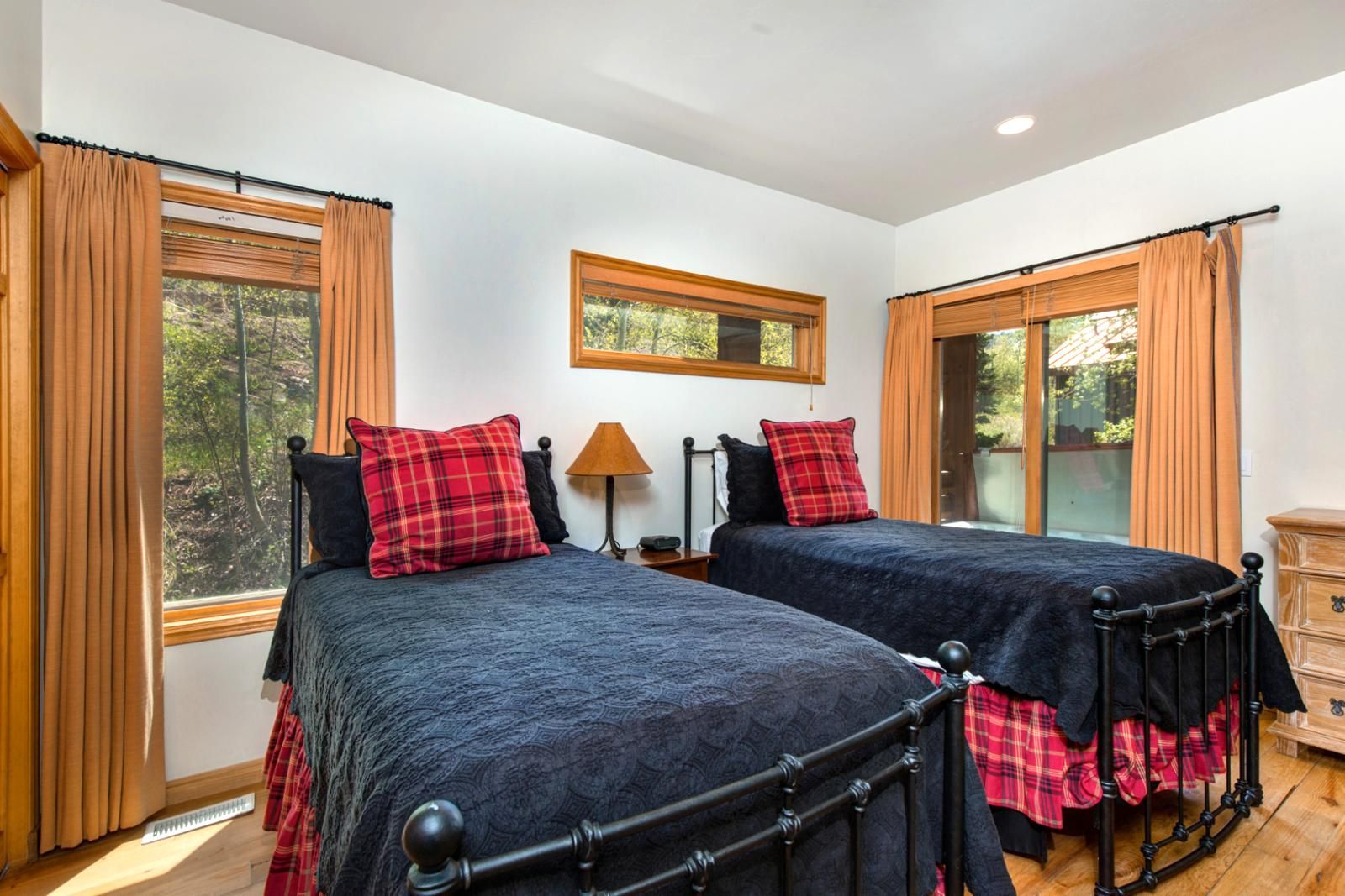 A double room with two beds, a nightstand, a lamp, and a dresser.