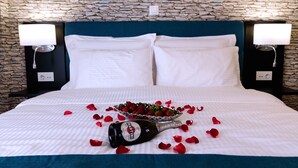 A neatly made bed with white linens, a bottle of Martini champagne, and a bowl of strawberries on a bed with rose petals scattered around. - Athens Chic House Apt B2 42sq.m 1st Floor (Athina)