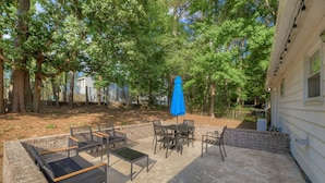 An outdoor patio with a concrete floor, surrounded by brick walls and trees. - Fort Jackson Family Abode 3BD 2BA Home RENOVATED (Columbia)