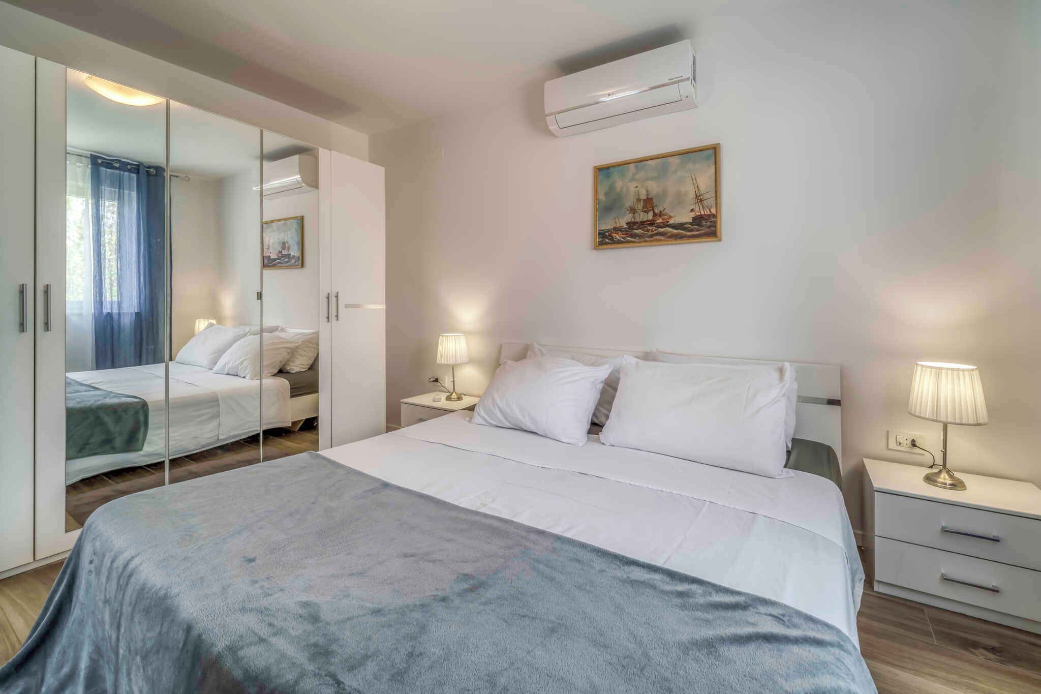 A bedroom with a bed, bedside tables, a wardrobe, and a painting on the wall.