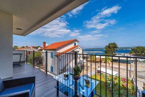 Un balcone con vista sul mare, un tavolo con una pianta e una sedia.