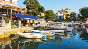 A waterfront restaurant with outdoor seating, boats docked in the background, and a clear view of the water.