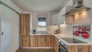 A modern kitchen with wooden cabinetry, a window, and a stainless steel range hood.