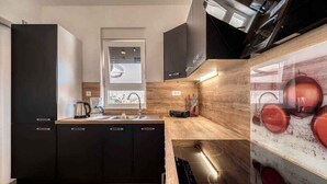 A modern kitchen with dark cabinetry, a window, and a built-in stove.