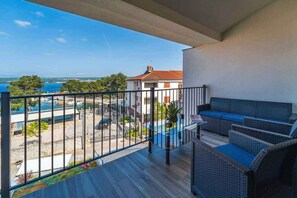 Un balcon avec vue sur la mer, des meubles d’extérieur et un bâtiment en arrière-plan.