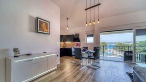 A modern apartment with a dining area, kitchen, and balcony with a view.