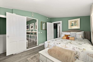 A bedroom with a bed, a desk, and a chair in the adjacent room.
