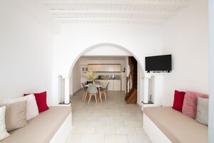 Una sala de estar moderna con un sofá, un comedor con sillas y una cocina al fondo.