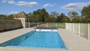 A rectangular swimming pool with a stone wall and a white fence surrounding it. - Magnificent gîte with private pool - 12 people - Gîtes Les Grandes Chaumes (Surgères)