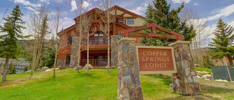 A lodge with a stone entrance sign, a red and beige building, and a clear sky.