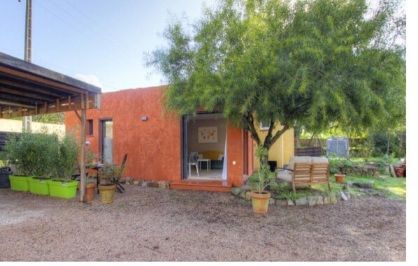 Il s’agit d’un petit bâtiment d’un seul étage, à l’extérieur rouge, doté d’un espace extérieur abrité. Un arbre se trouve devant le bâtiment, et on peut apercevoir plusieurs plantes en pot.