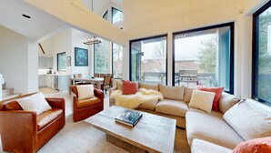 Ein geräumiges Wohnzimmer mit einer großen Couchgarnitur, einem Couchtisch und einem Essbereich mit einer Küche im Hintergrund.