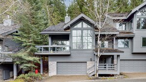Ein modernes, zweistöckiges Haus mit Garage, Balkon und einer Fassade aus Naturstein.