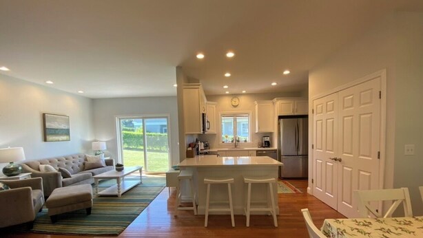 A modern kitchen with white cabinets, a central island, and a dining area with a table and chairs.