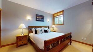 A bedroom with a wooden bed, two bedside tables with lamps, a painting on the wall, and a window with blinds. - 3 Bedroom plus Den / 2.5 Bath Mountain Star Townhome, Private Hot Tub, Quiet Slope Side location (Whistler)