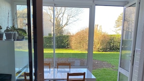 Een eethoek met een tafel en stoelen, en een schuifdeur naar een tuin.